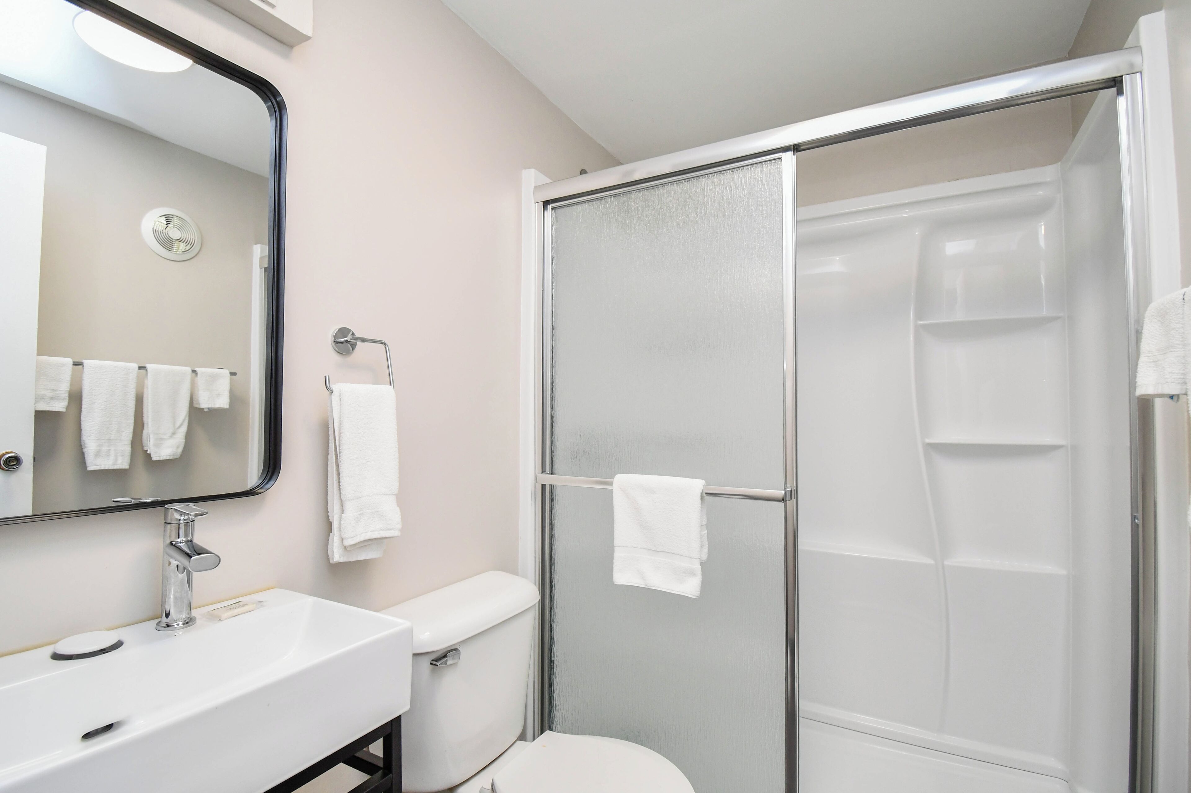 Een badkamer met een wit wastafel, toilet en een douchecabine met glazen wanden.
