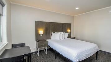 Una habitación de hotel con cama, mesitas de noche, escritorio y una silla.