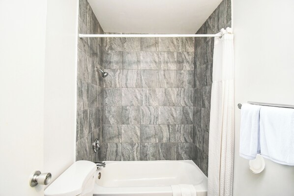 Une salle de bain moderne équipée d’une baignoire, d’une douche et de toilettes.