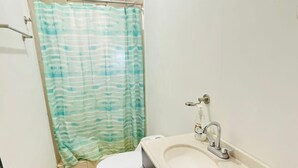 Een badkamer met toilet, wastafel en douchegordijn.