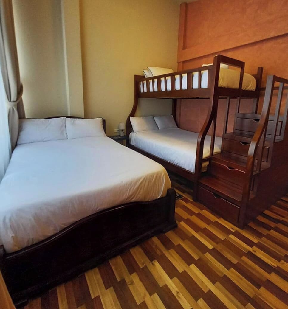 Une chambre avec un grand lit, un lit plus petit et un lit superposé.