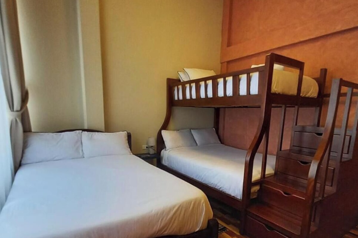 Una habitación con una cama grande, una cama más pequeña y una litera.
