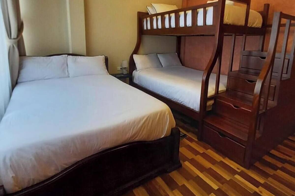 Una habitación con una cama grande, una cama más pequeña y una litera.