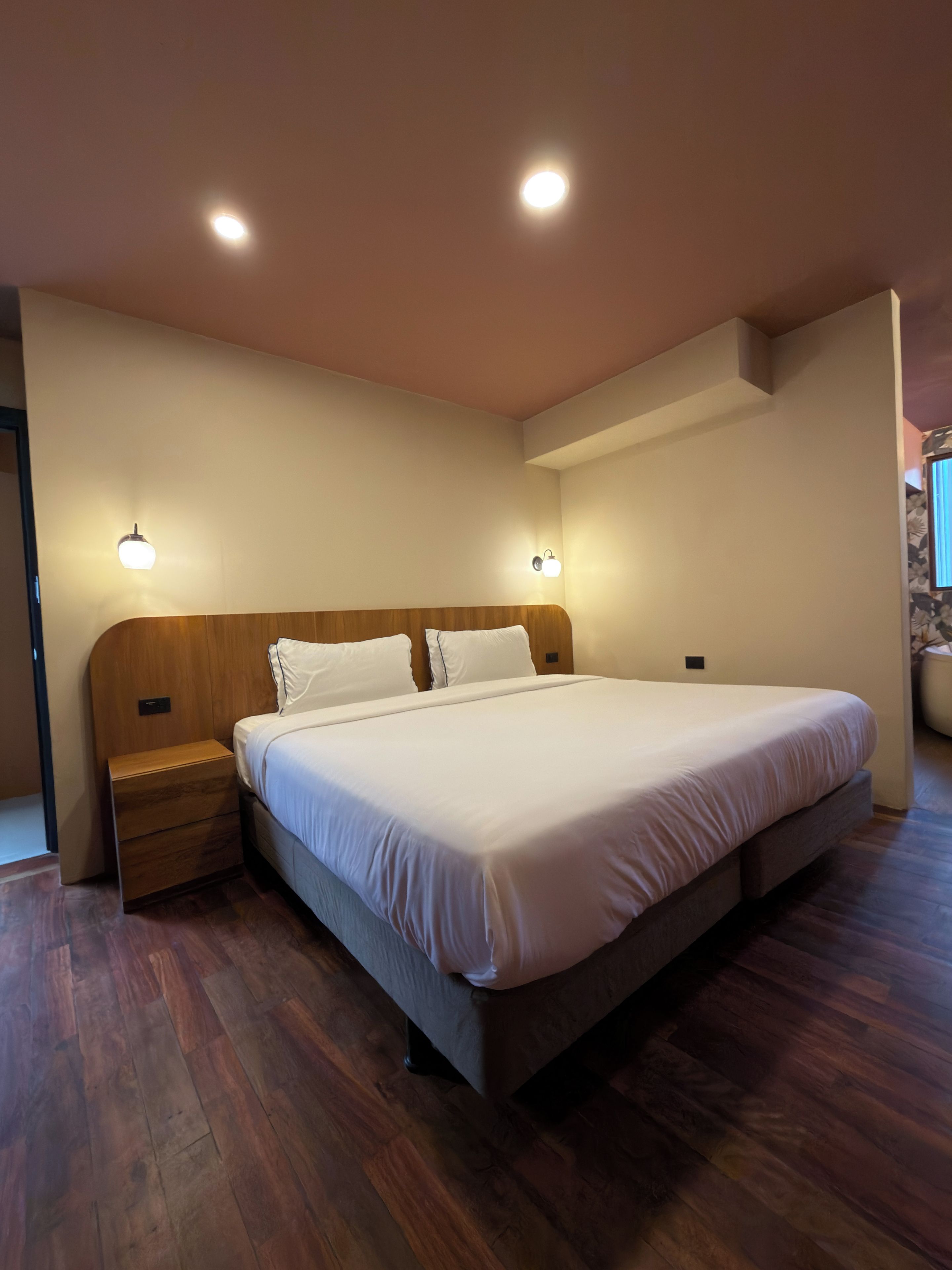 A bedroom with a wooden headboard, a single bed, bedside tables, and wall-mounted lighting.