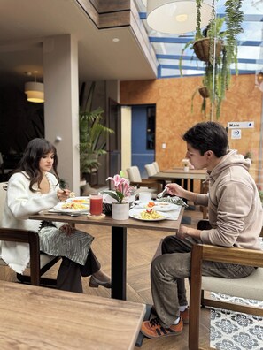 A dining area with tables, chairs, and hanging plants. - Hotel Casa Agave (Banos de Agua Santa)