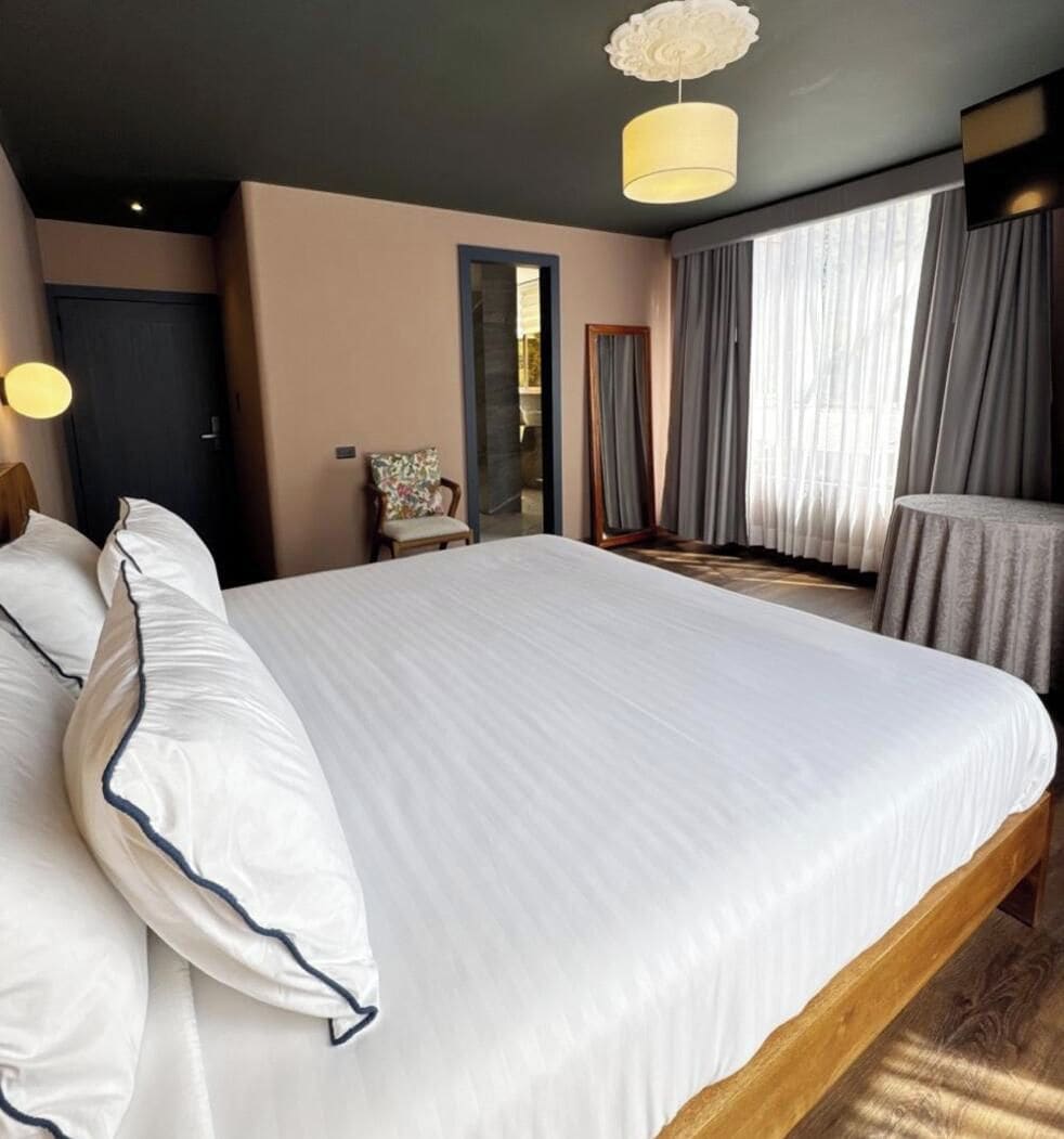 Une chambre d’hôtel avec un grand lit, une chaise, une table et une vue sur l’extérieur.