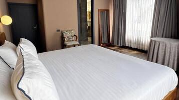 Une chambre d’hôtel avec un grand lit, une chaise, une table et une vue sur l’extérieur.