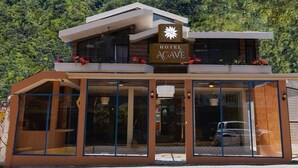 A modern hotel with a sign reading "HOTEL AGAVE" and a tagline "toda una experiencia". The building has large glass windows and a flat roof. - Hotel Casa Agave (Banos de Agua Santa)