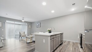 Una cocina moderna con una isla central, electrodomésticos integrados y un comedor con mesa y sillas blancas.