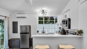 Una cocina moderna con una isla central, electrodomésticos de acero inoxidable y un ventanal que proporciona luz natural.