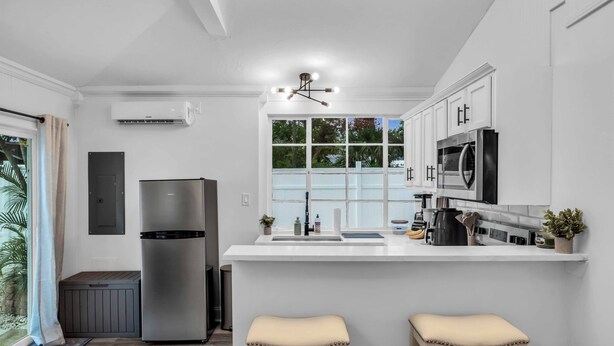 Una cocina moderna con una isla central, electrodomésticos de acero inoxidable y un ventanal que proporciona luz natural.
