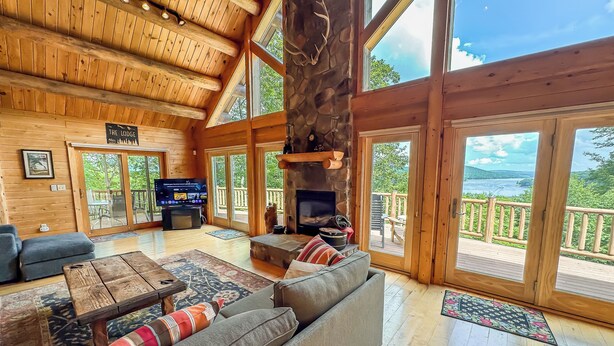 A spacious lodge interior with a large fireplace, comfortable seating, and a television.