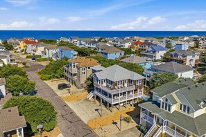 A coastal residential area with houses, a clear sky, and the ocean in the background. - We Are Beachin | 580 ft to the beach | Private Pool, Hot Tub, Dog Friendly, and Community Pool (Corolla)