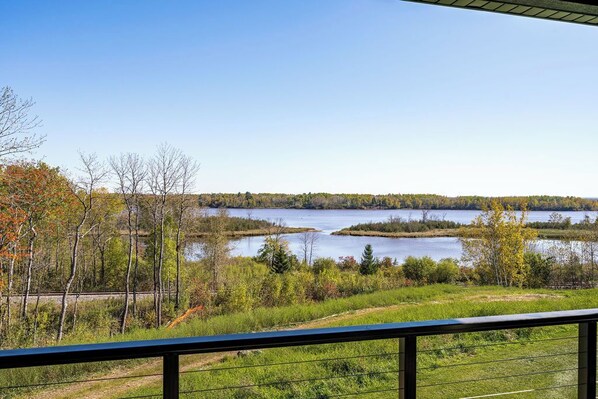 A lakeside view from a balcony with a railing, trees, and a clear sky. - RiverWest Island View - Sauna - River View - Upper level (Duluth)