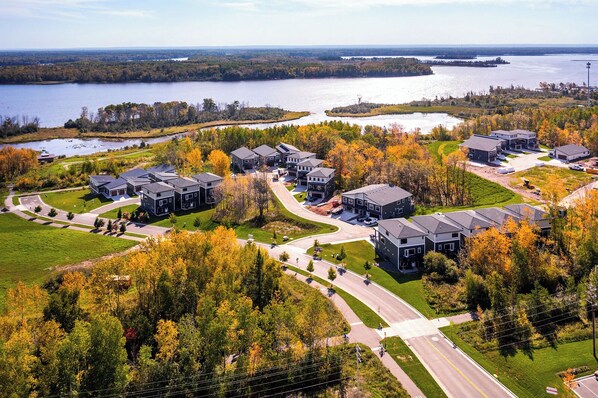 Un quartier résidentiel avec des maisons modernes, une route et une étendue d’eau en arrière-plan.