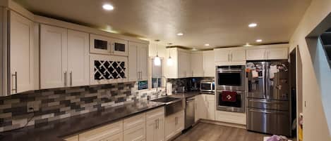 A modern kitchen with white cabinets, a black countertop, and stainless steel appliances.