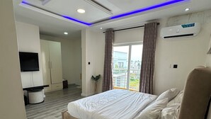Un dormitorio moderno con una cama grande, un televisor montado en la pared y un equipo de aire acondicionado.