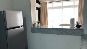 Una cocina moderna con refrigerador empotrado, una ventana con cortinas y encimera de mármol.