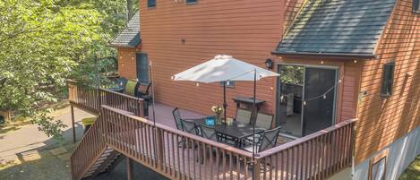 A two-story house with a deck, a patio with outdoor furniture, and a large sliding glass door.