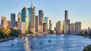 A city skyline with modern high-rise buildings and a river with sailboats.