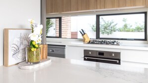 A modern kitchen with a marble countertop, a framed artwork, and a vase with flowers.