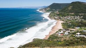 A coastal town with a beach, houses, and hills.