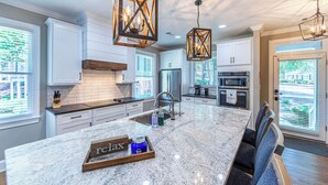 Una cocina moderna con armarios blancos, una isla grande e iluminación colgante.