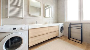 Une salle de bain moderne équipée d’un lave-linge, d’un évier et d’un miroir.
