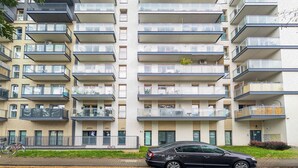 A multi-story residential building with balconies, a car parked in front, and a clear sky. - Riverwalk Charming Apartment (Wrocław)