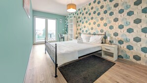 A modern bedroom with a bed, bedside tables, a desk, and a patterned wall. - Riverwalk Charming Apartment (Wrocław)
