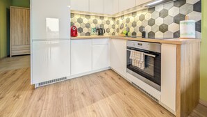A modern kitchen with white cabinets, a wooden countertop, a stainless steel oven, and a hexagonal tile backsplash. - Riverwalk Charming Apartment (Wrocław)