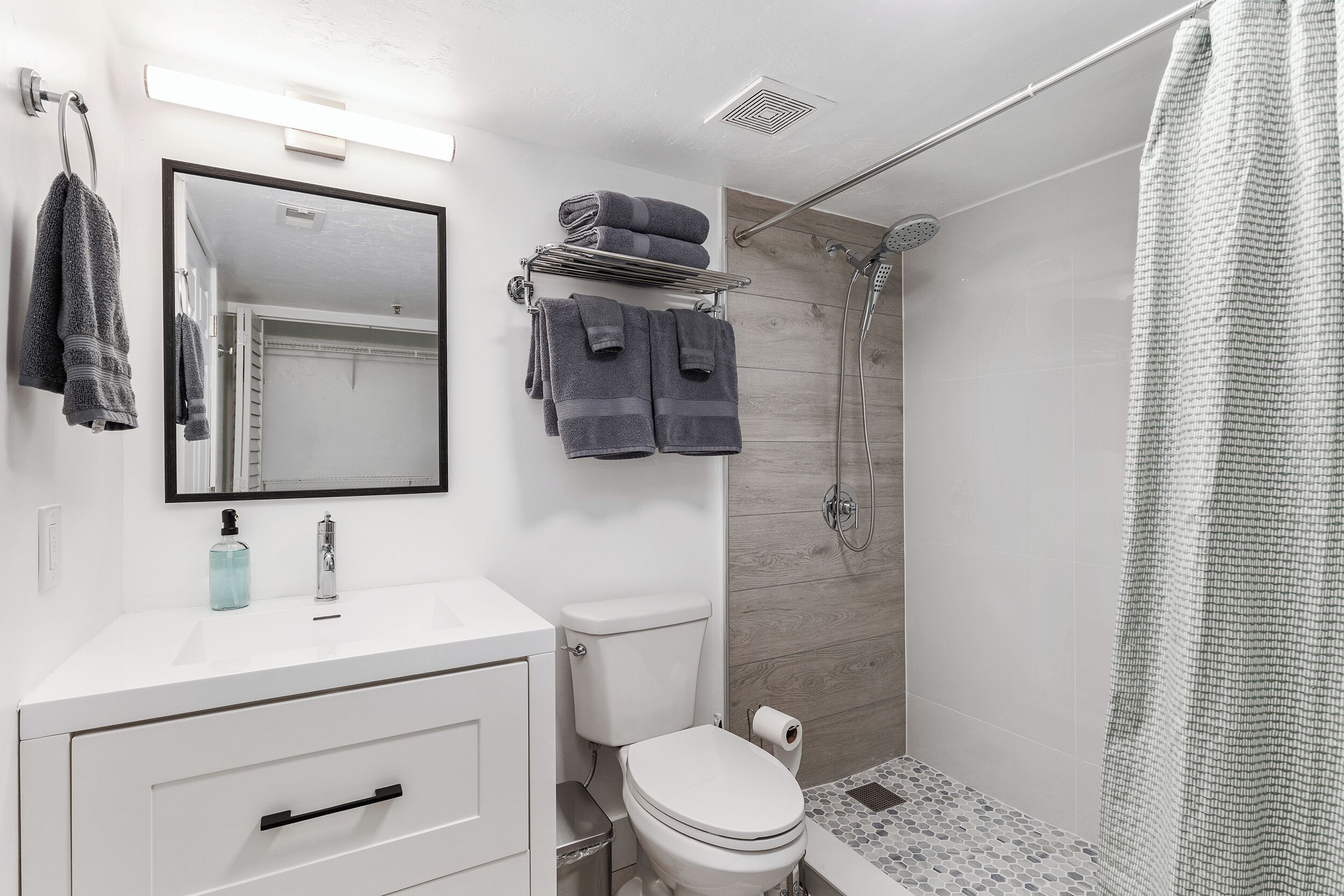 A modern bathroom with a white sink, a toilet, and a shower.