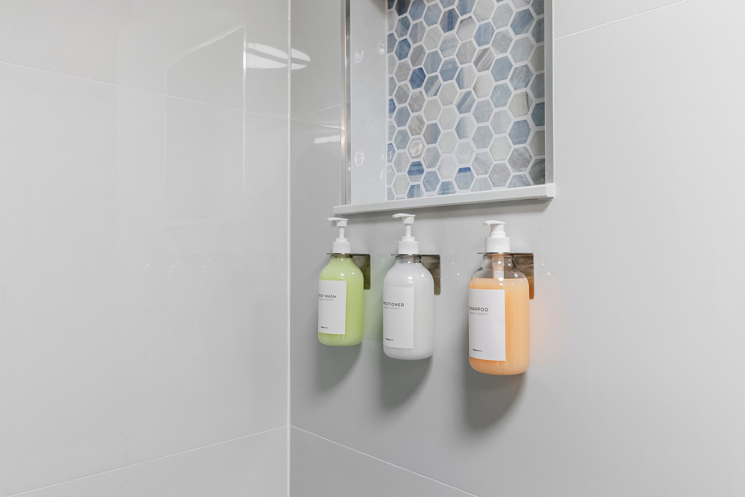 Un baño con ducha, puerta de cristal y tres artículos de tocador.