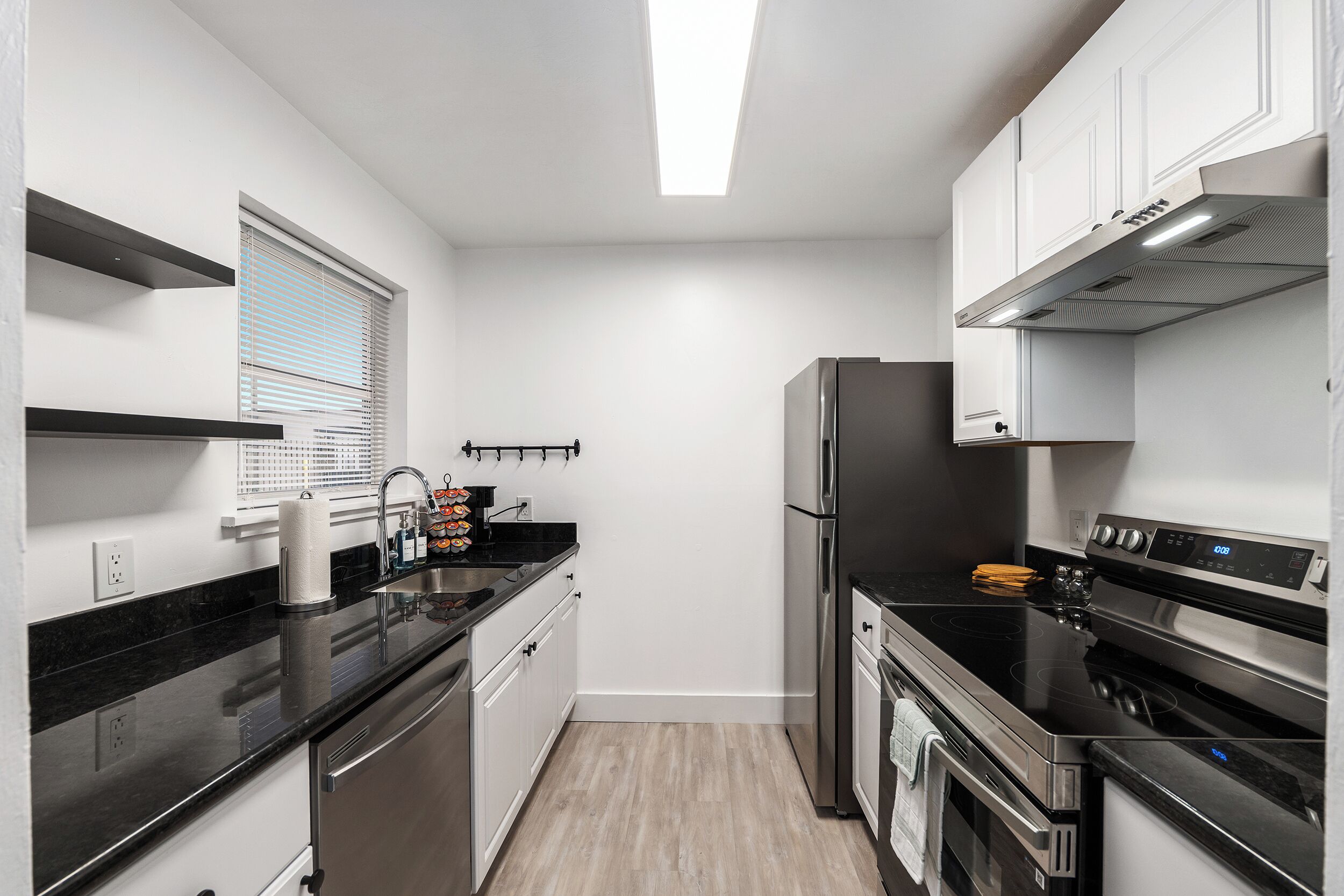 Una cocina moderna con electrodomésticos de acero inoxidable, encimera negra y armarios blancos.