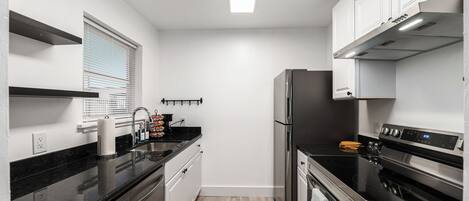 Una cocina moderna con electrodomésticos de acero inoxidable, encimera negra y armarios blancos.