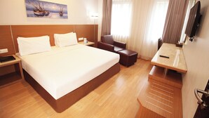 Een hotelkamer met een groot bed, een bureau, een stoel en een televisie.