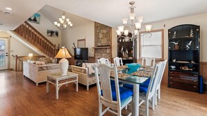 Un salon spacieux comprenant un coin repas, un escalier et un téléviseur.