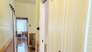 A hallway with wooden flooring, white doors, and a view into a room with a window and a chair. - 3BDR Blue Mountains Hideaway in Central Katoomba (Katoomba)