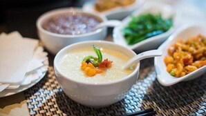 A table with various dishes including a bowl of soup with a green garnish, a bowl of beans, a dish with green vegetables, and a plate of mixed food. - Joya Hotel Shanghai Xu Jia Hui (Shanghai)