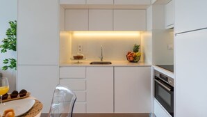 Una cocina moderna con armarios blancos, un lavamanos de acero inoxidable y un horno empotrado.
