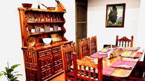 A dining area with a wooden table and chairs, a cabinet with glassware, and a potted plant. - Ocean Colors Villa (San Pedro Pochutla)