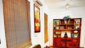 A living room with a sofa, a bookshelf, and an air conditioning unit. - Ocean Colors Villa (San Pedro Pochutla)