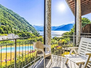 Ein Balkon mit Blick auf einen See und Berge, ein Pool sowie Sitzgelegenheiten im Freien.