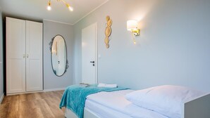 Quarto com cama, guarda-roupa, espelho e luzes fixadas na parede.