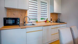 Uma cozinha moderna com armários brancos, micro-ondas preto, pia e fogão.