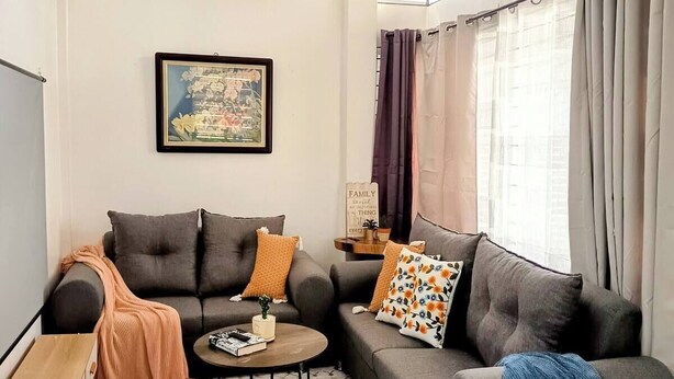 Una sala de estar moderna con un sofá gris, una mesita de centro y un ventilador de techo.