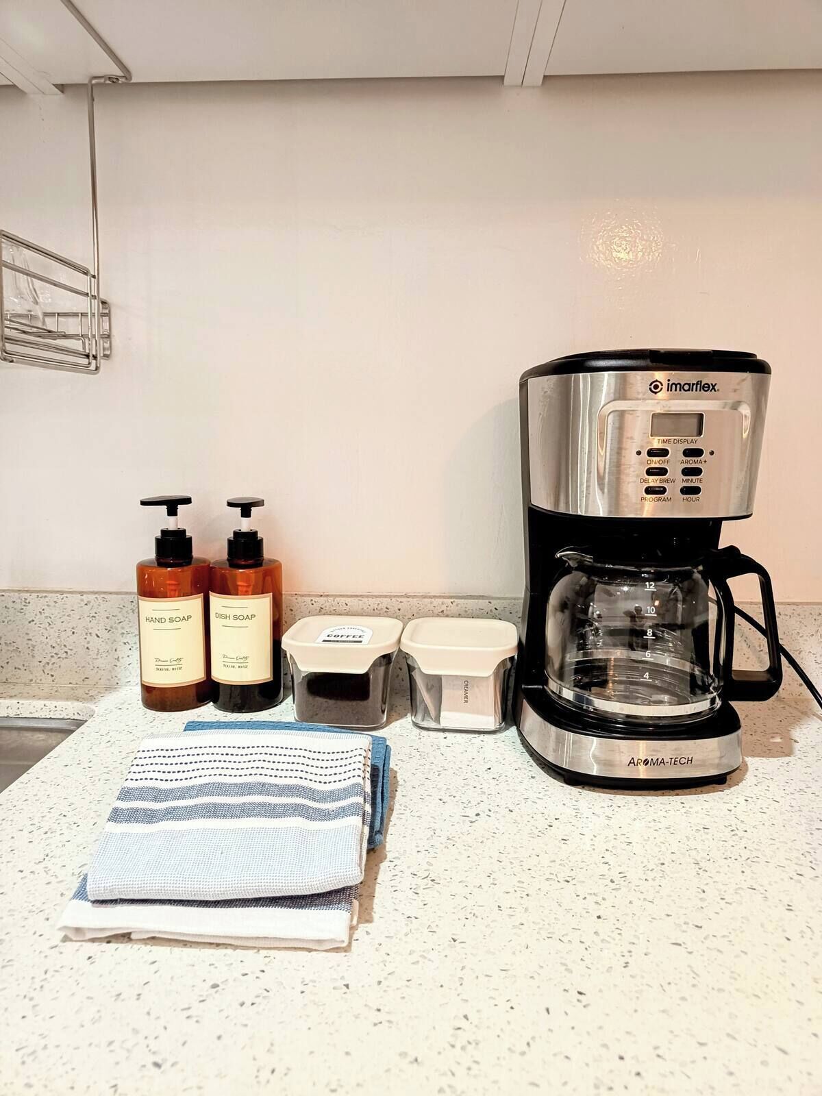 A kitchen counter with a coffee maker, hand soap, dish soap, and coffee containers.