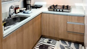 Una cocina compacta con armarios de madera, cocina a gas, cafetera y fregadero.