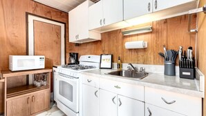A modern kitchen with white cabinets, a stove, a microwave, and a sink. - Huckleberry Lodge Mountain Getaway Near Banff! (Harvie Heights)