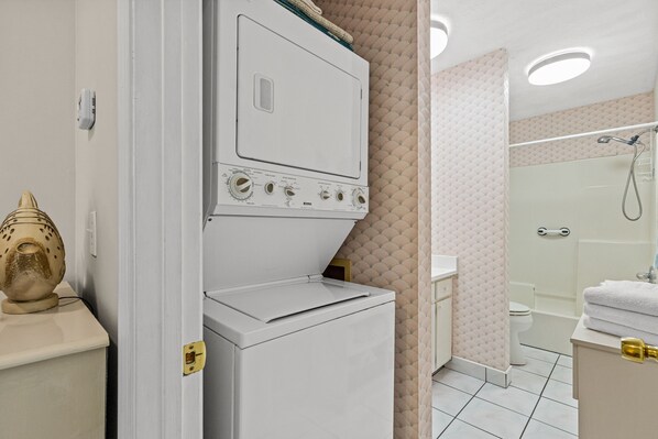 Un baño equipado con lavadora, ducha e inodoro.